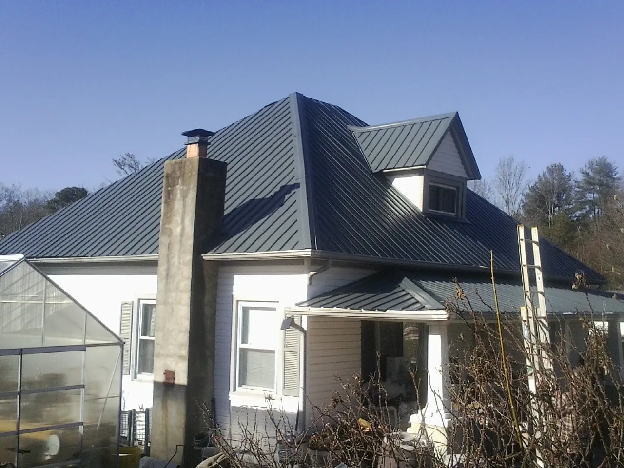 Dark blue standing seam metal roof on a white farmhouse with dormer — Slate & Tile Roof Repair by Roofing Brothers in University Place