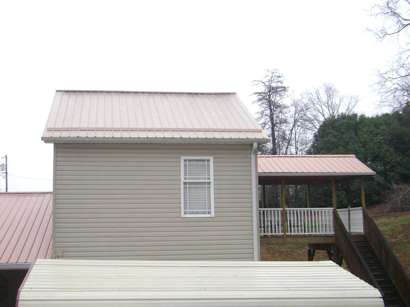 Tan metal roofs on a two story addition and attached porch, from a Roof Replacement job in University Place