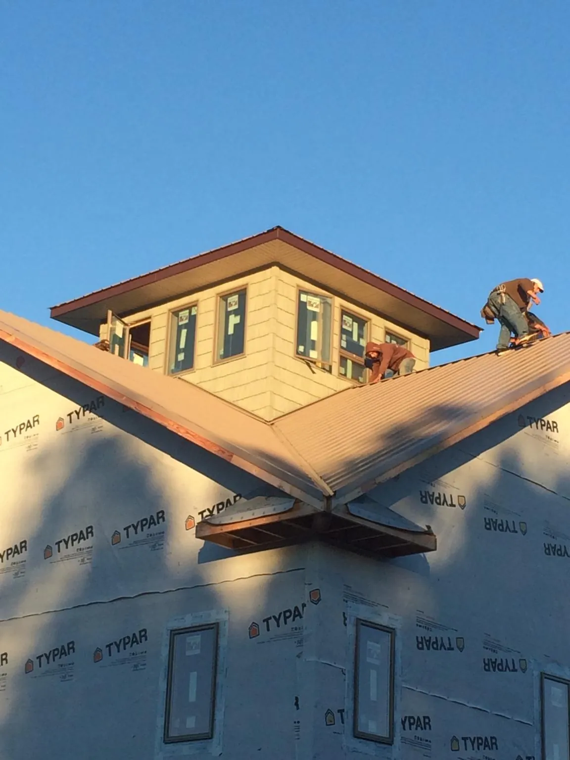 Roofers working around a rooftop cupola on a new metal roof at sunset — Roof Waterproofing in University Place by Roofing Brothers